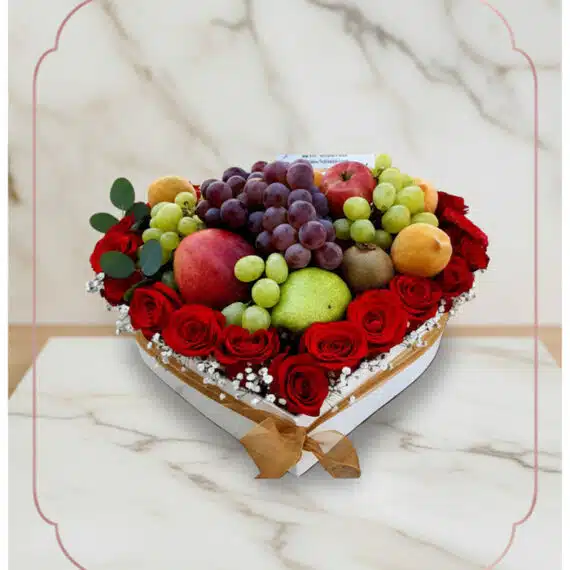 ARMANI: Arreglo Exquisito de Frutas y Rosas Rojas en Corazón Arreglo floral ARMANI con frutas frescas variadas y rosas rojas dispuestas en una caja blanca en forma de corazón, ideal para