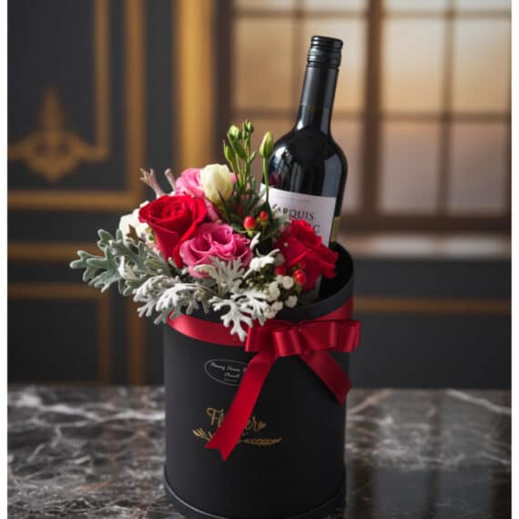 Arreglo Floral BENTO con Rosas y Vino: Elegancia para Regalar Arreglo floral BENTO con rosas rojas y rosadas, follaje verde y una botella de vino tinto en una caja negra con lazo rojo, so
