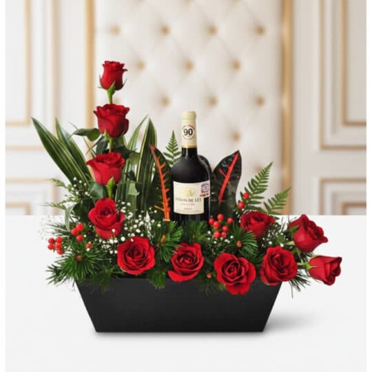 Arreglo floral CINZIA con 12 rosas rojas frescas, follaje verde variado y una botella de vino tinto, presentado en una base n