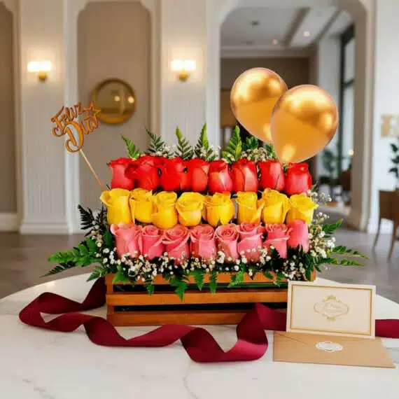 Arreglo floral Escala con rosas rojas, amarillas y rosas en caja de madera, con follaje, globos dorados y tarjeta de felicita