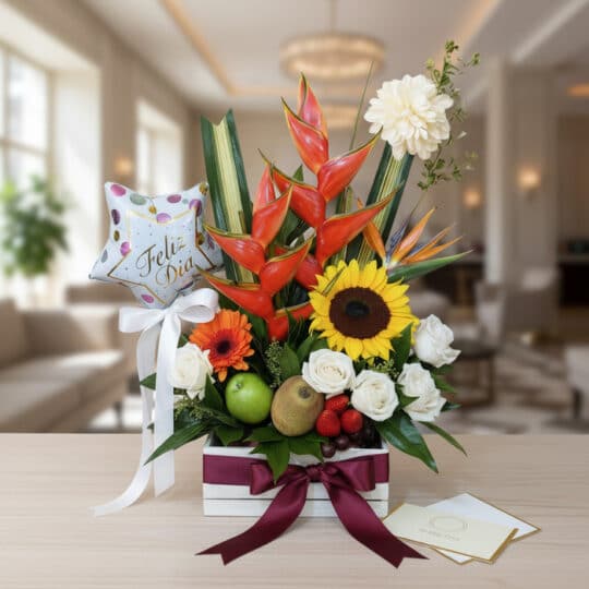Arreglo floral exótico con heliconias, girasoles, rosas blancas y frutas frescas como kiwi y fresas, presentado en una base d