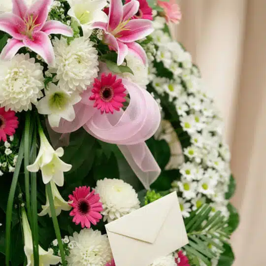 Detalle de la Corona Fúnebre Solemne "Homenaje a Mathias" con lirios blancos y rosas, crisantemos y gerberas, con cinta satin